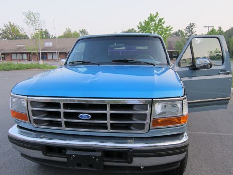 2001 Ford Crown Victoria - Front view of a blue Ford F-Series truck parked in a lot with a building in the background.