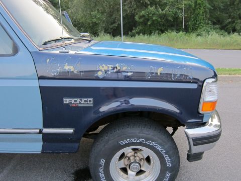 2001 Ford Crown Victoria - Side view of a Ford Bronco XL with visible paint damage on the hood and fender.