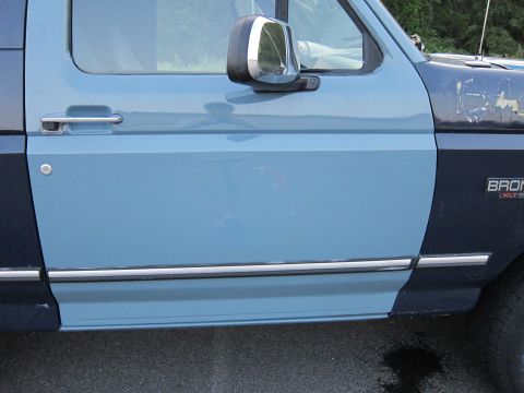 2001 Ford Crown Victoria - The side panel of a two-tone blue Ford Bronco, showing the 'BRONCO XLT' emblem.