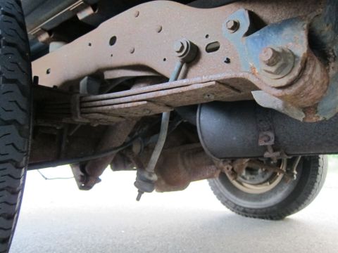 2001 Ford Crown Victoria - Undercarriage view of a vehicle's rear axle and suspension system, showing significant rust.