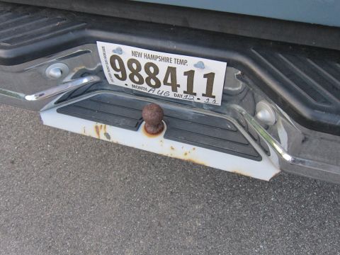 2001 Ford Crown Victoria - A temporary New Hampshire license plate is attached to the rear bumper of a vehicle, showing a tow hitch.