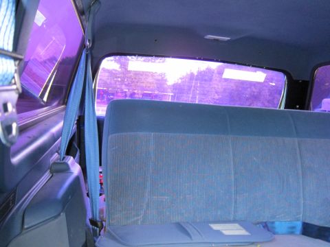 2001 Ford Crown Victoria - Interior view of a vehicle with blue seats and purple tinted windows, showing a seatbelt mechanism.