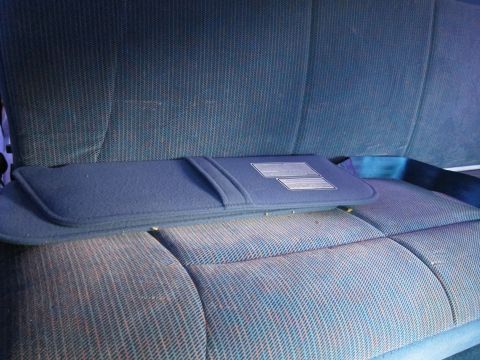 2001 Ford Crown Victoria - The interior of a vehicle shows a rear seat and a folded sun visor with some text on it.