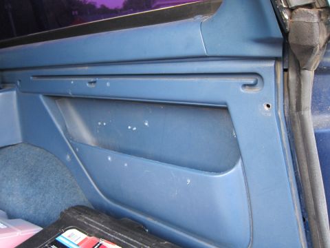 2001 Ford Crown Victoria - Close-up view of a blue interior door panel, showing a storage pocket and some faint markings.
