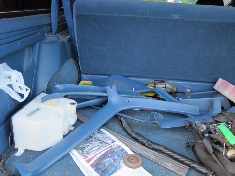 2001 Ford Crown Victoria - Interior parts and a fluid reservoir are stored in the cargo area of a vehicle.