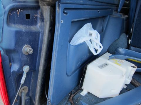 2001 Ford Crown Victoria - The interior of a vehicle's trunk, blue plastic panels and a white fluid reservoir with some text.