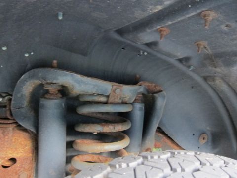 2001 Ford Crown Victoria - The front suspension system of a vehicle, a coil spring and shock absorber, displays signs of rust and age.