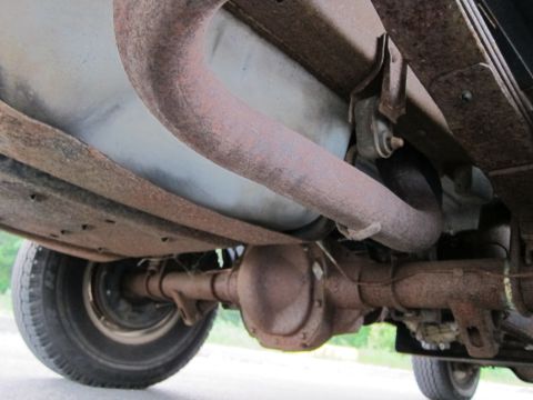2001 Ford Crown Victoria - The underside of a vehicle reveals a rusty exhaust system and rear axle assembly.