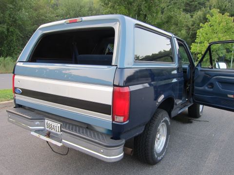 2001 Ford Crown Victoria - Rear view of a blue and silver two-tone Ford Bronco, showing the license plate and open driver's door.