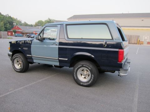 2001 Ford Crown Victoria - A two-tone Ford Bronco is parked in a lot, showing its side profile.