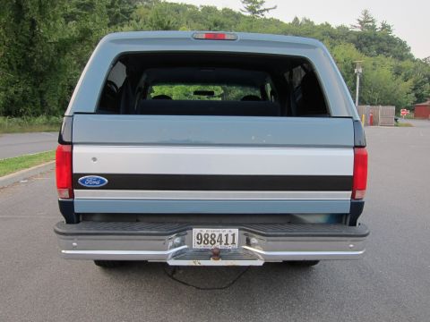 2001 Ford Crown Victoria - The rear view of a blue Ford Bronco shows its distinctive silver stripe and Ford emblem on the tailgate.