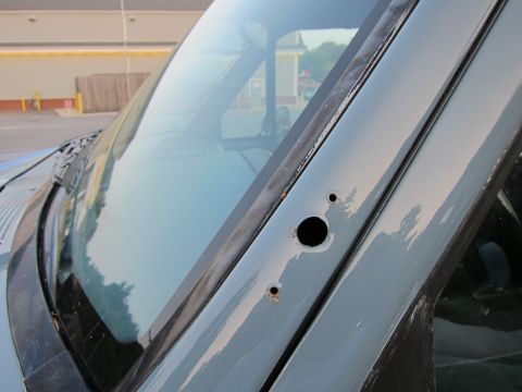 2001 Ford Crown Victoria - The photo shows a close-up of a vehicle's windshield pillar, revealing two drilled holes and some rust.
