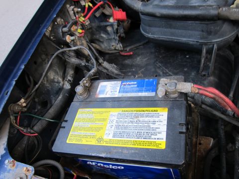 2001 Ford Crown Victoria - The engine bay shows an ACDelco battery with warning labels and connected red cables.