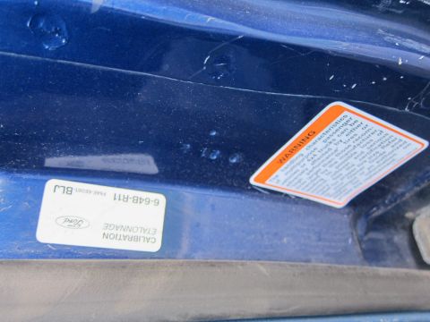 2001 Ford Crown Victoria - Close-up of a Ford calibration sticker and a warning label on a blue painted surface.