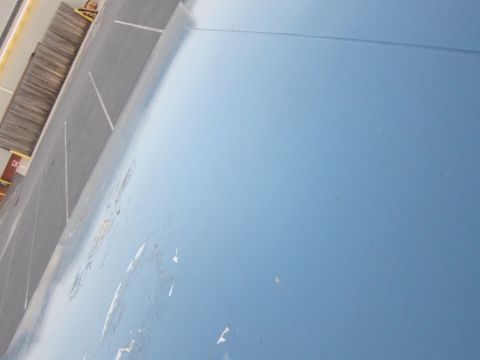 2001 Ford Crown Victoria - A close-up of a blue vehicle's body panel shows signs of wear and tear, with a parking lot visible in the distance.