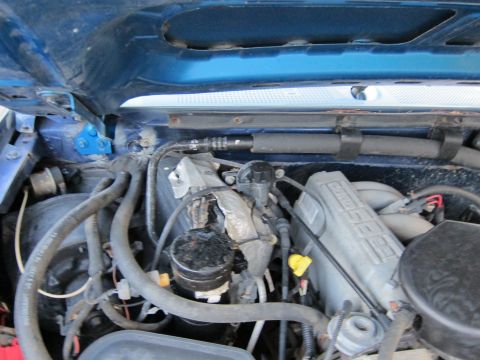 2001 Ford Crown Victoria - The engine compartment of a blue vehicle is shown, numerous hoses and mechanical parts.