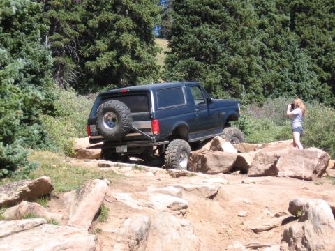 1995 Ford Bronco - A Ford Bronco navigates a rocky off-road course with a spectator capturing the moment.