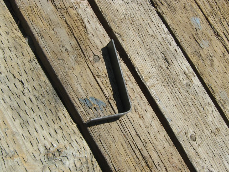 L-shaped metal bracket resting on weathered wooden planks