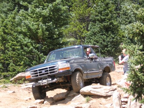 1995 Ford Bronco - A Ford Bronco is shown off-roading on a rocky mountain path.