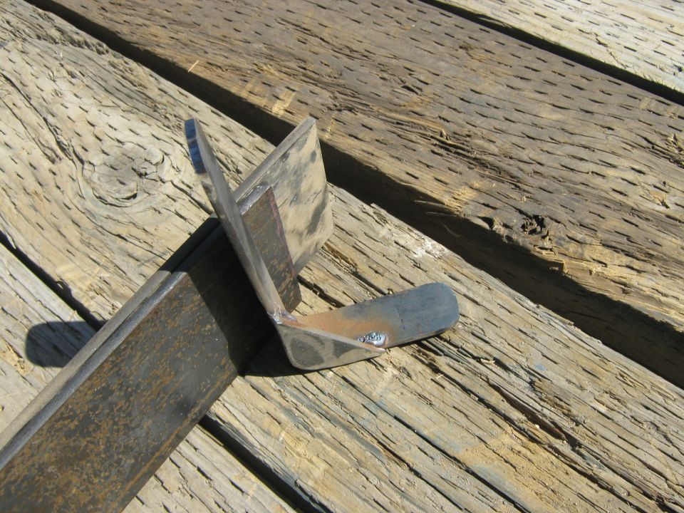 Welded metal bracket with two angled pieces, resting on wooden planks