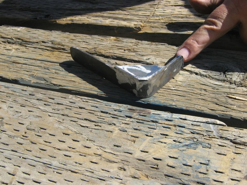 metal bracket on wood planks, finger pointing to it