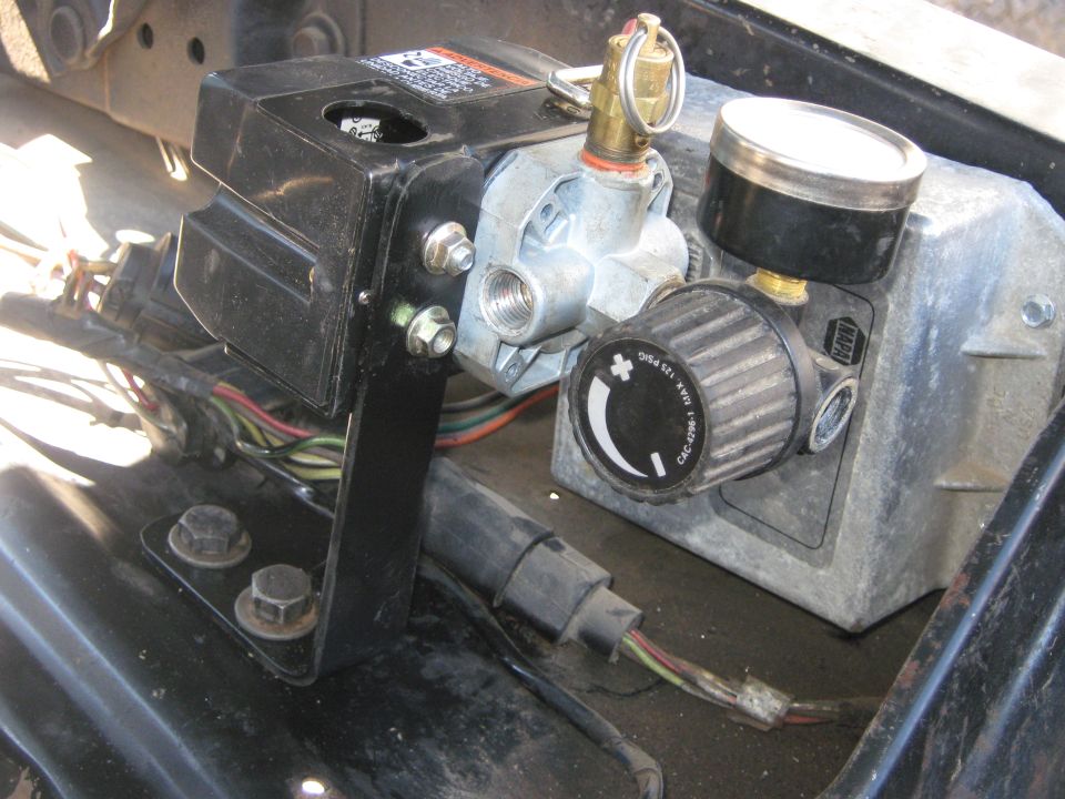 Air compressor regulator with gauge and adjustment knob. Wires are visible