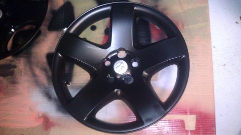 2006 Dodge Charger - A black wheel cover is shown, with another partially visible. The surface appears to be undergoing some modification.