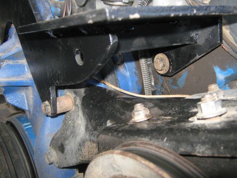 1972 Ford F-250 - Close-up view of a black metal engine bracket attached to a blue engine block, showing bolts and a pulley.