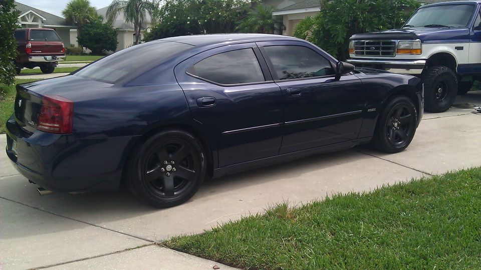 Dark blue Dodge Charger sedan, side/rear view, black wheels, tinted windows, in driveway