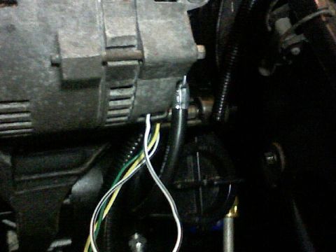 1987 Mercury Grand Marquis - Close-up view of an alternator with its wiring harness disconnected, showing the internal components and external connections.