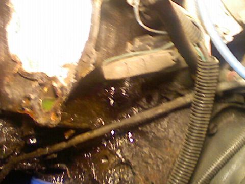 1987 Mercury Grand Marquis - Close-up view of a corroded engine bay with a visible fluid leak and electrical wiring.