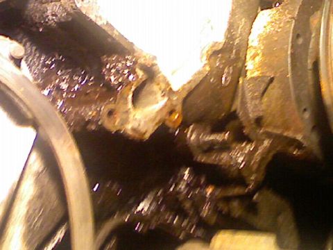 1987 Mercury Grand Marquis - A close-up view of a heavily soiled and corroded engine component, likely from a vehicle's internal mechanics.