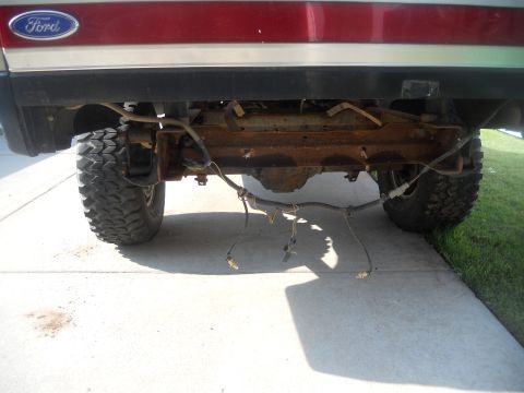 1991 Ford Bronco - The rear axle and suspension components of a 1991 Ford Bronco are visible, with some wiring hanging loose.