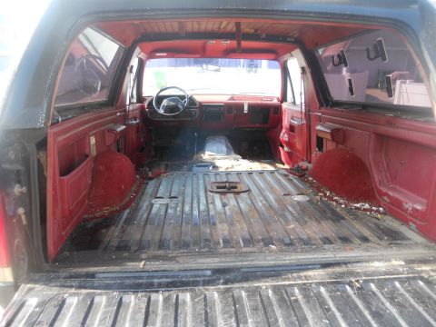 1991 Ford Bronco - The interior of a 1991 Ford Bronco shows red upholstery and an empty cargo area, suggesting it may have been used for hauling.