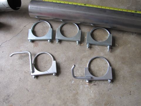 1995 Ford Bronco - A metal exhaust pipe and a set of five pipe clamps are laid out on a concrete surface.