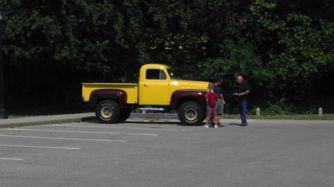 1989 Ford Bronco - A two-tone pickup truck is parked in a lot with people standing nearby.