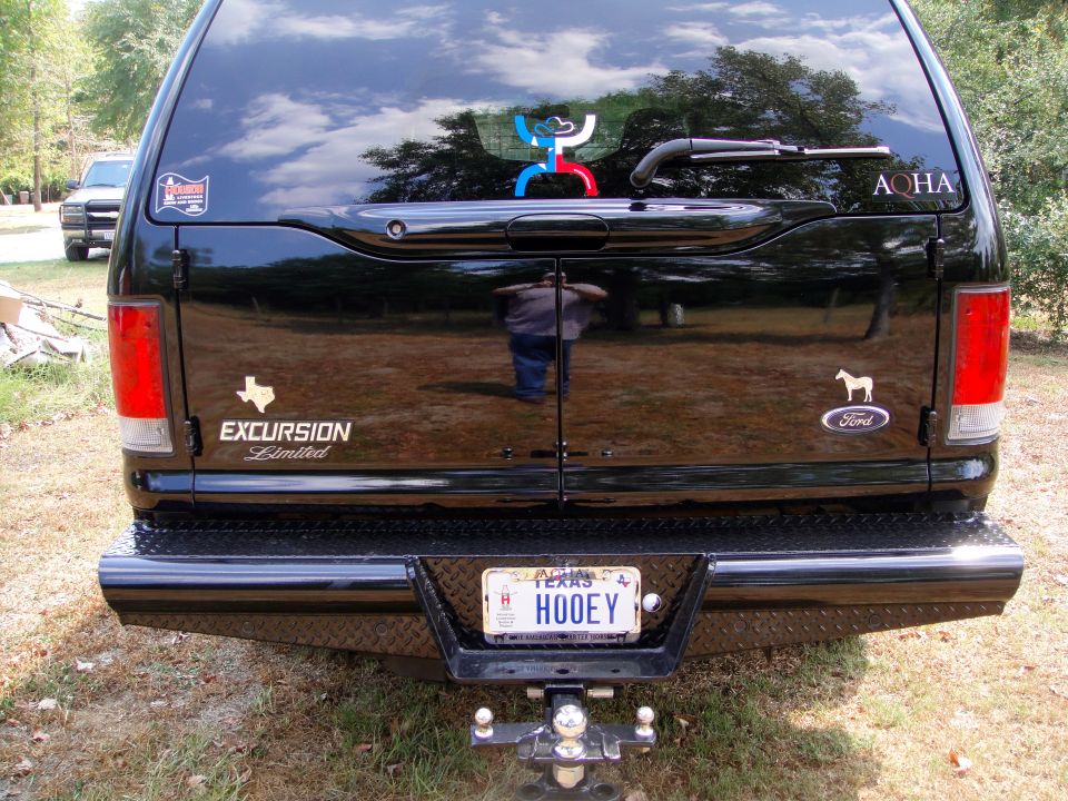 Black Ford Excursion Limited SUV rear view, diamond plate bumper, Texas license plate HOOEY, trailer hitch