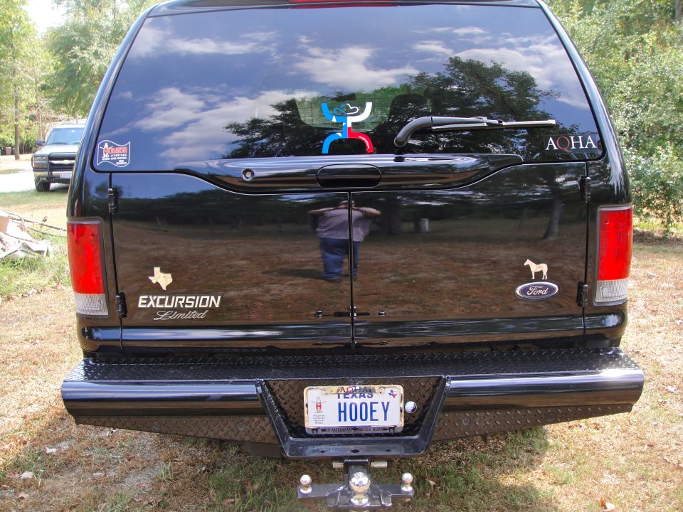 Black SUV rear with 'EXCURSION Limited' badge and Texas license plate 'HOOEY'
