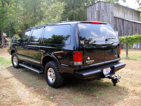 2005 Ford Excursion - The rear of a black 2005 Ford Excursion SUV is shown parked outdoors next to a rustic wooden barn.