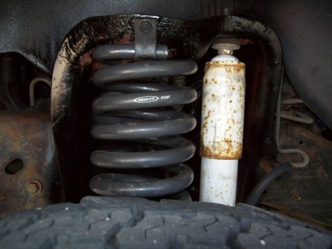 1993 Ford F-150 - Close-up of a vehicle's front suspension, showing a coil spring and a shock absorber.