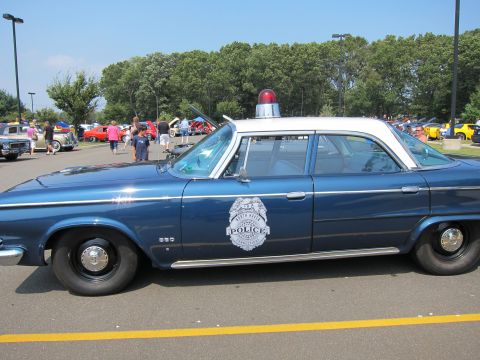 1991 Ford LTD Crown Victoria - Side profile of a blue police sedan with white roof, single dome light and a Police door shield in a sunny lot.