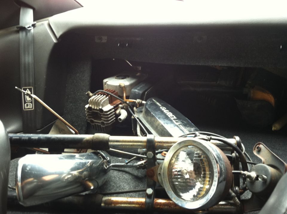 Disassembled Garelli moped with engine, headlight and chrome exhaust loaded in a car cargo area