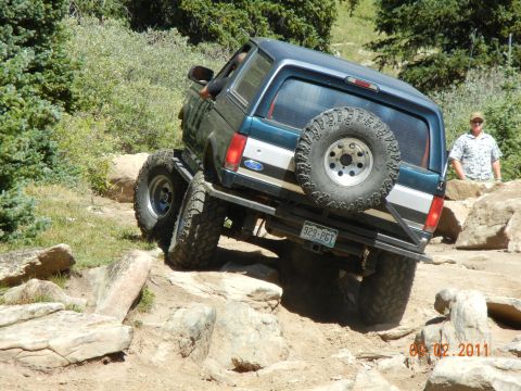 1996 Ford Bronco - A modified Ford Bronco navigates a challenging rocky terrain on a sunny day.