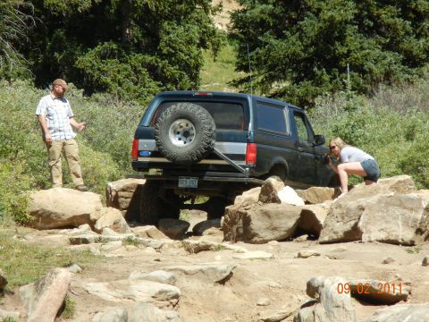 1996 Ford Bronco - 1996 Ford Bronco tackling an off-road trail with a man and woman observing.