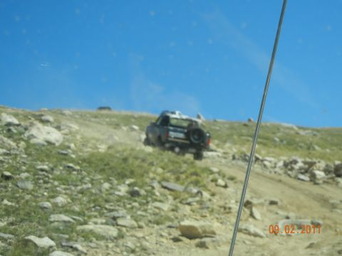 1996 Ford Bronco - 1996 Ford Bronco navigating a steep, rocky terrain on a sunny day.
