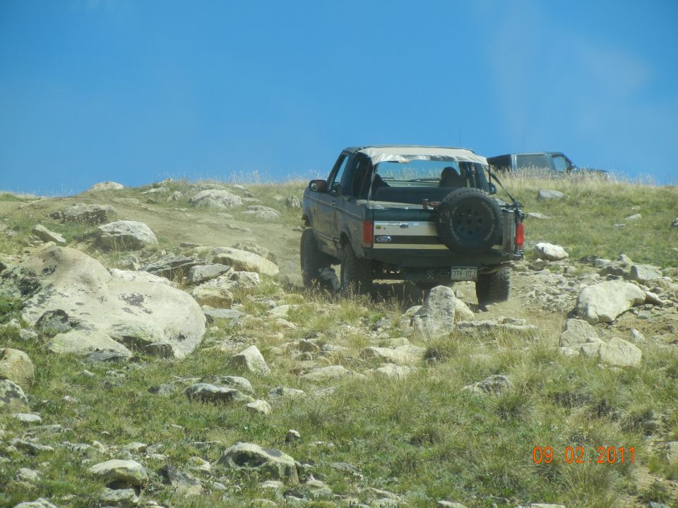Ford Bronco with soft top driving on rocky trail, another SUV behind it