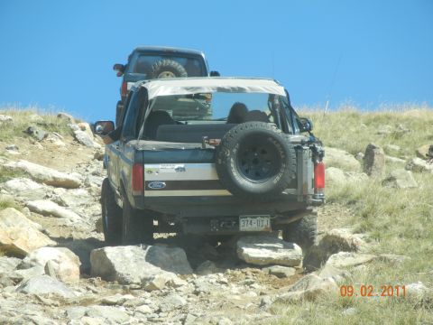 1996 Ford Bronco - A 1996 Ford Bronco navigates a challenging rocky terrain, with another vehicle following closely behind.