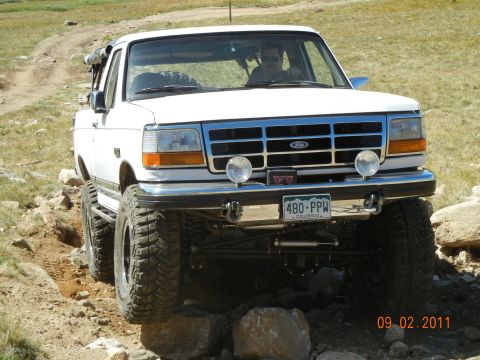 1996 Ford Bronco - This modified Ford truck navigates a challenging off-road path with large tires and lifted suspension.