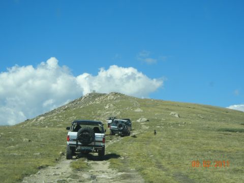 1996 Ford Bronco - Multiple Ford Broncos ascend a mountain trail on a clear day.
