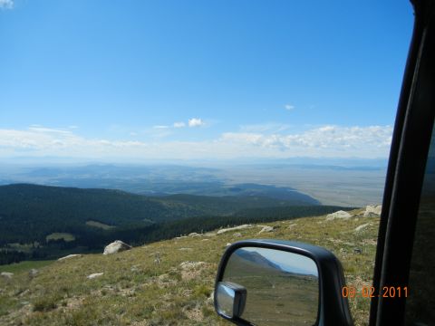 1996 Ford Bronco - View from a vehicle's side mirror shows a vast landscape under a blue sky with clouds. A watermark is visible in the corner.